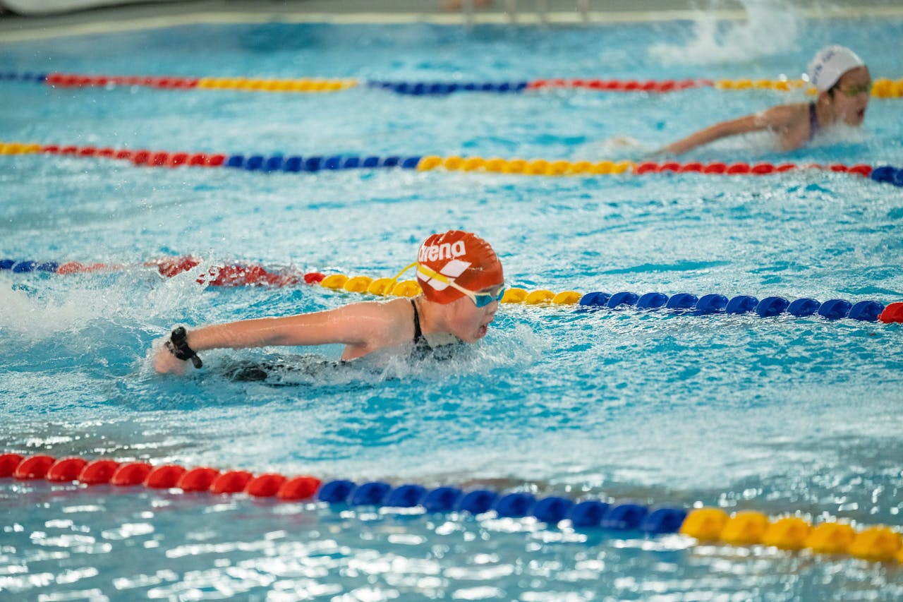 Swimmers compete in a vibrant indoor pool race, focusing on freestyle strokes.