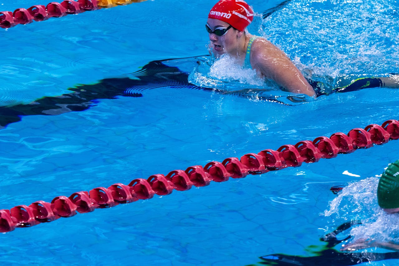 Swimmer in competitive race at indoor swimming pool with clear blue water.